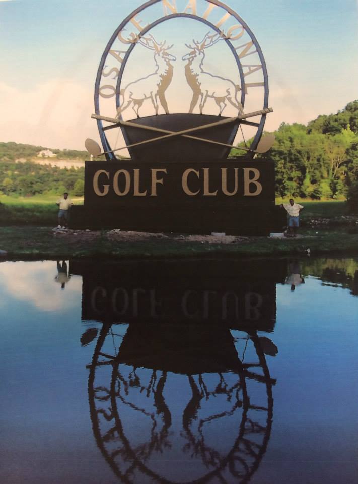 Golf club sign with deer silhouettes reflected in water at sunset