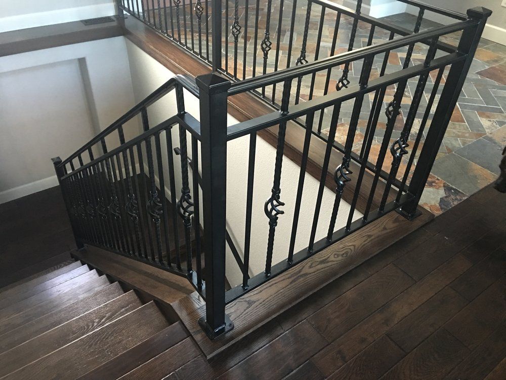 Stairwell with dark wood steps and black metal railing overlooking a tiled floor below