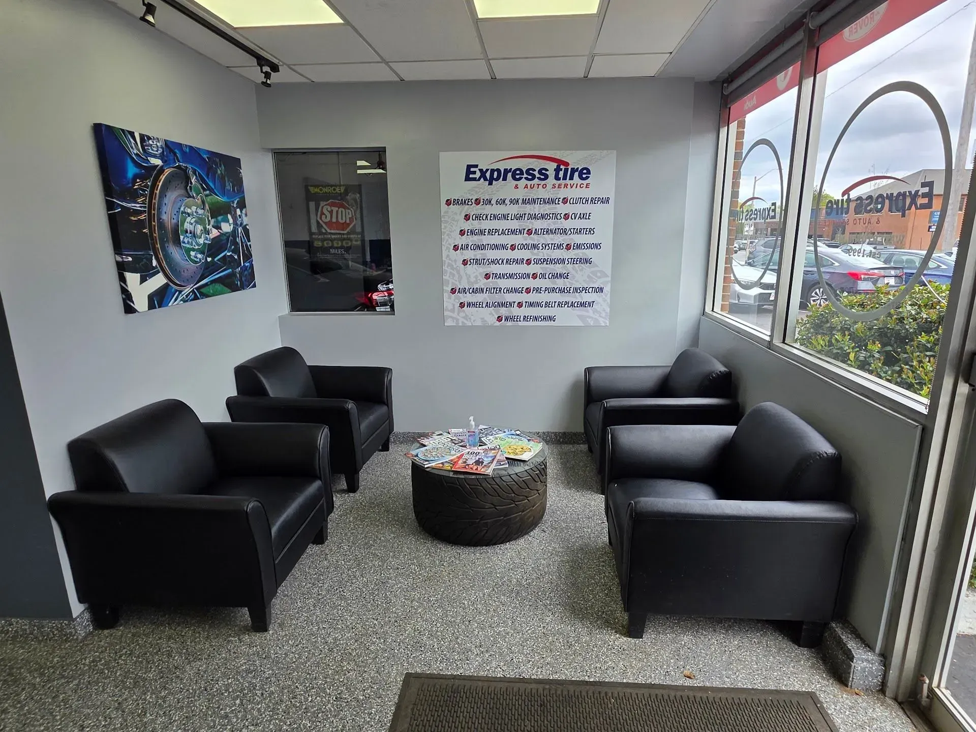 Small Waiting Room with Black Chairs, a Round Table, and Wall Signs | Express Tire & Auto Service