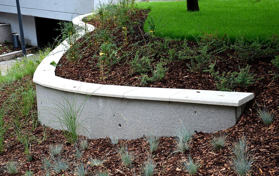 a concrete bench sitting in the middle of a garden