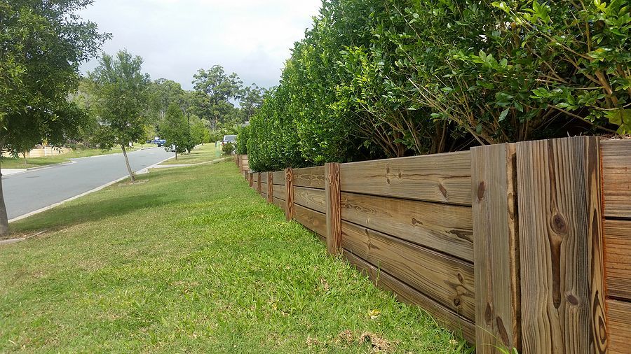 a wooden fence in the grass next to a street