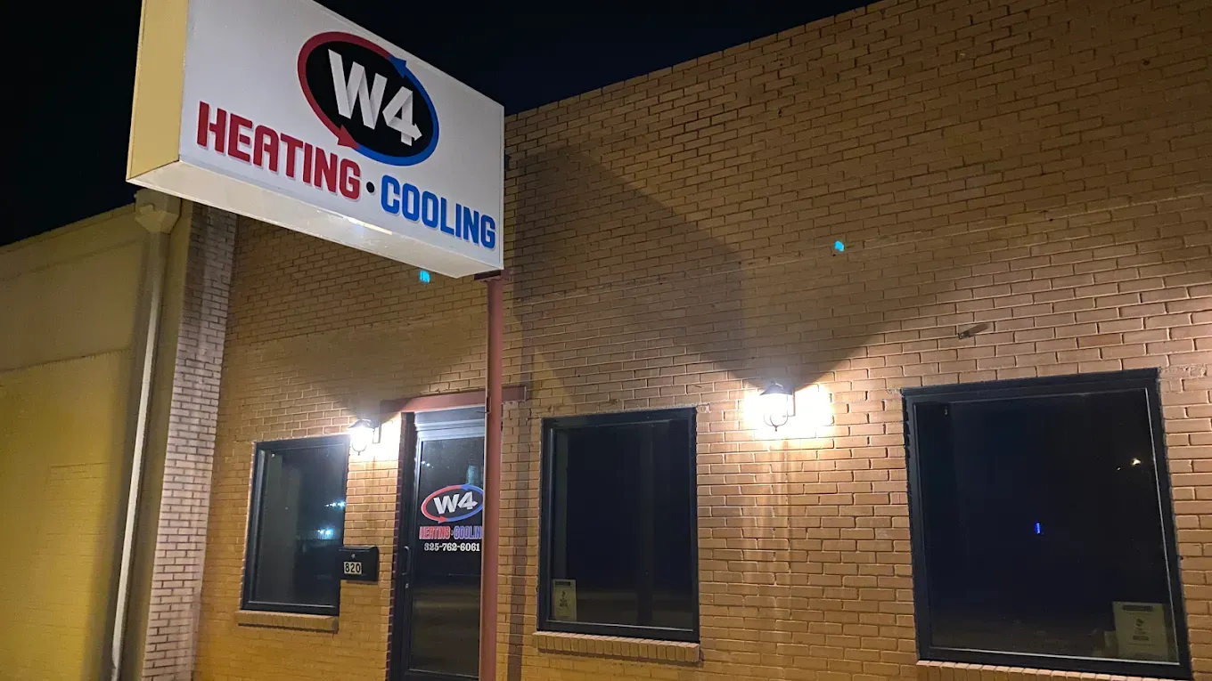 Nighttime exterior of W4 Heating-Cooling office on a brick building with lit entrance and windows