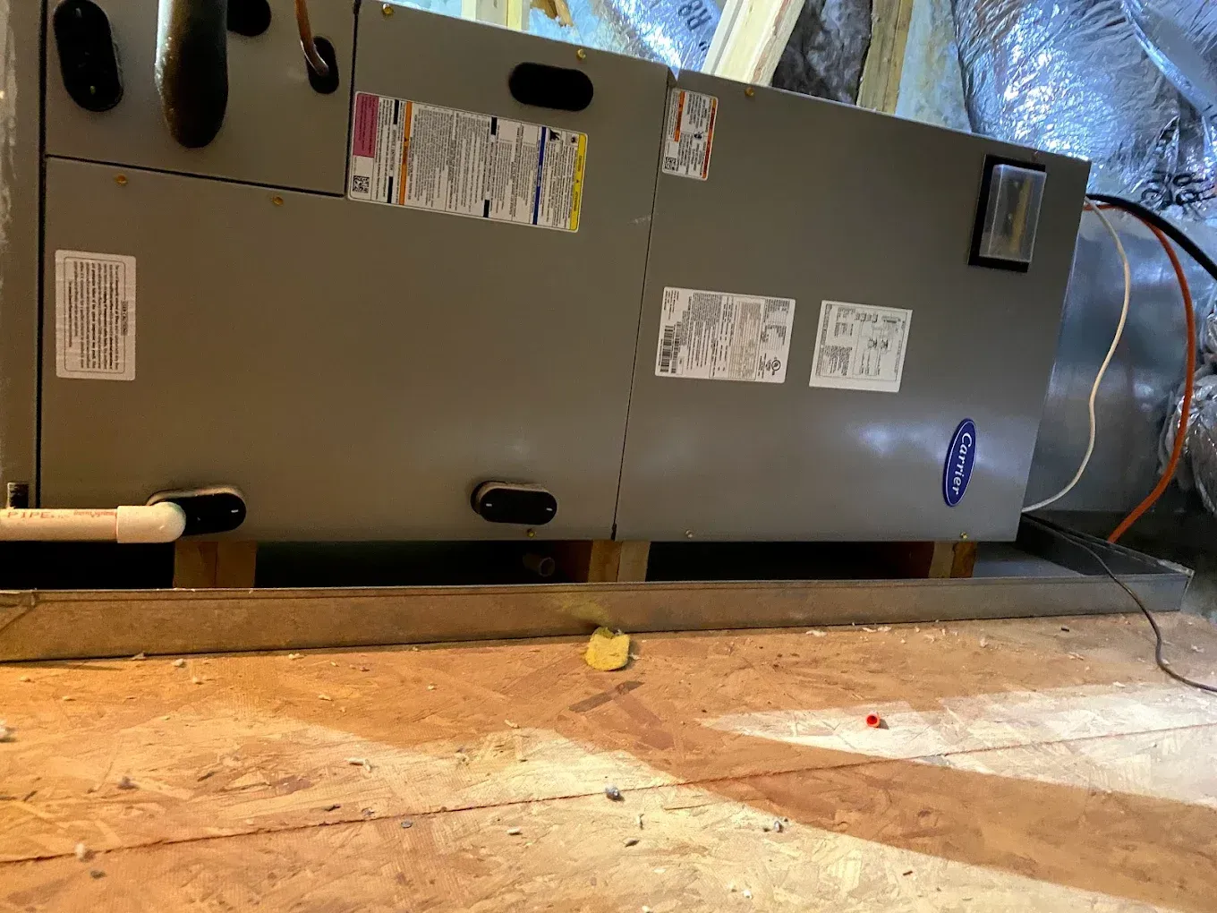 Gray HVAC furnace in a basement, with ducts and pipes visible on a concrete floor.