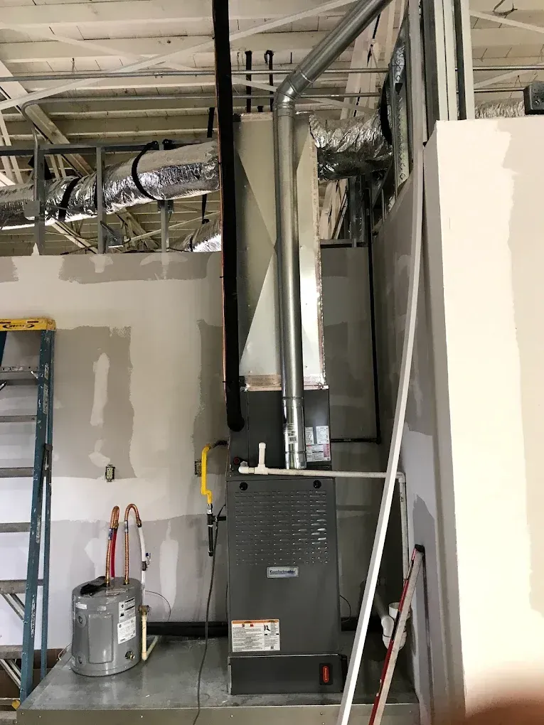 Mechanical HVAC unit installed in a partially finished room with exposed ceiling and ductwork
