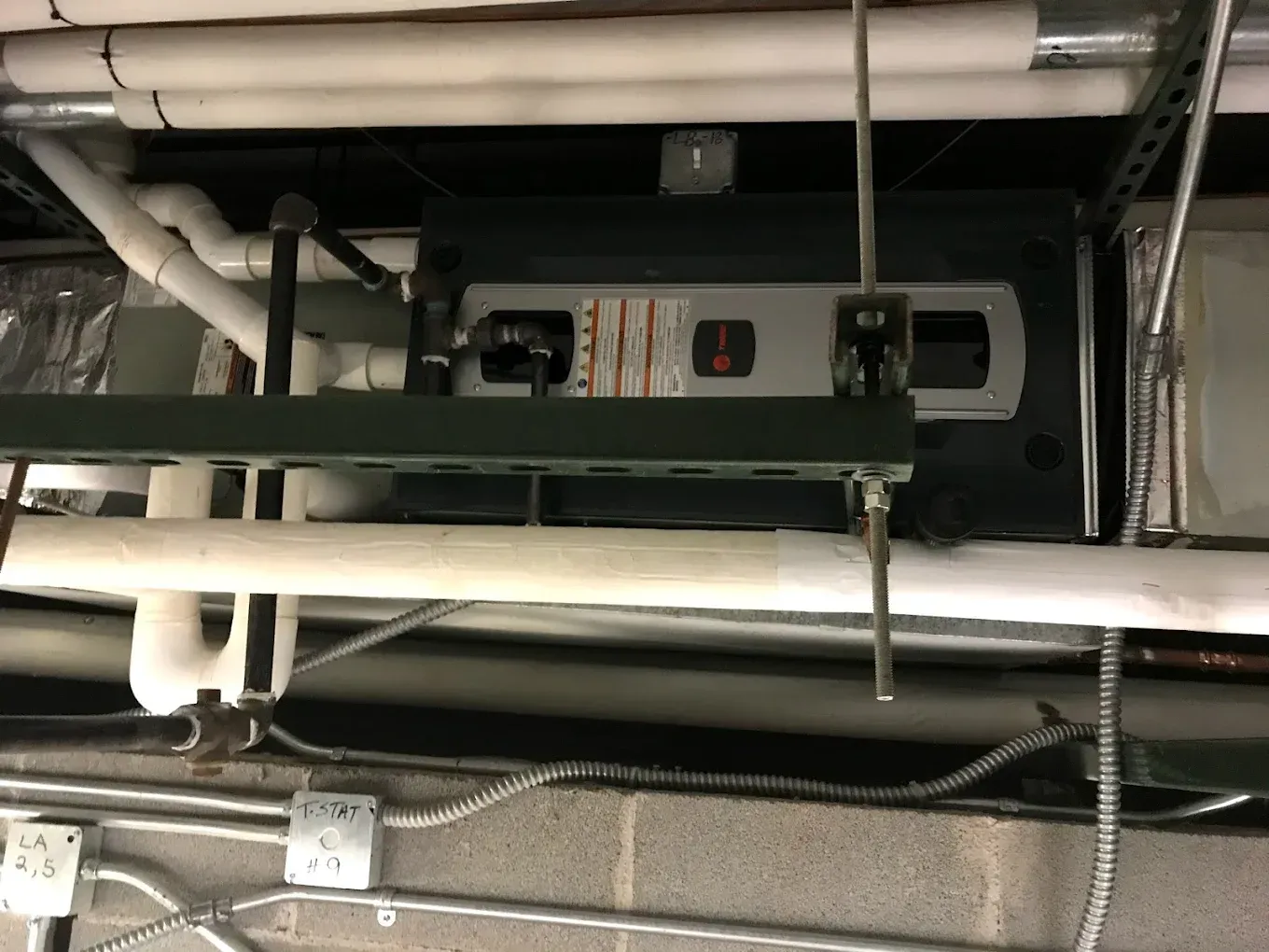 Industrial piping and a mounted control unit inside a utility ceiling space