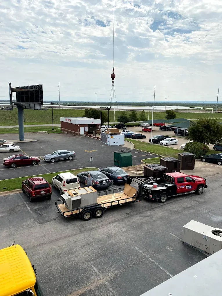Parking lot with several trucks and cars beside a grassy waterfront under a cloudy sky