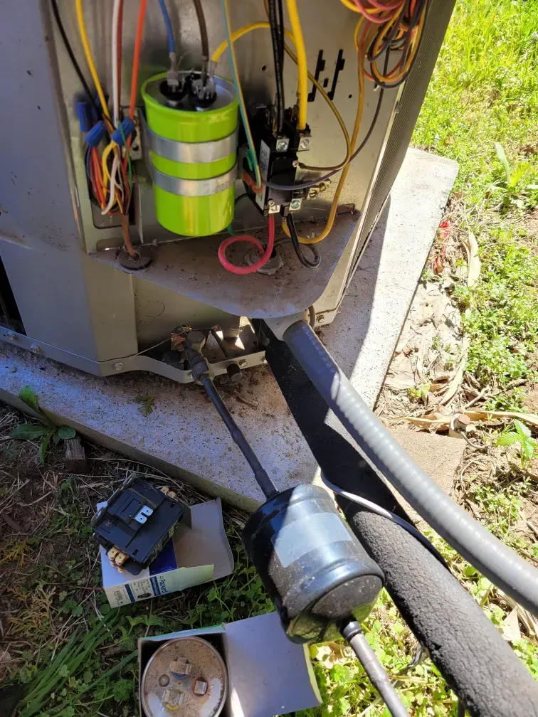 Open electrical cabinet with exposed wiring and tools on the ground beside conduit hoses