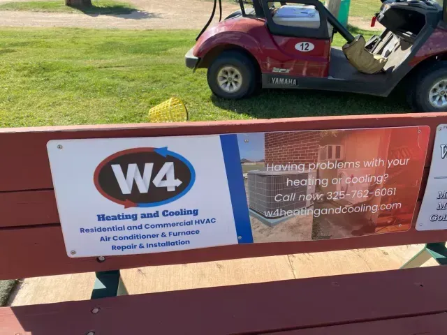 W4 crisis support bench sign in a park, with red golf cart in the background
