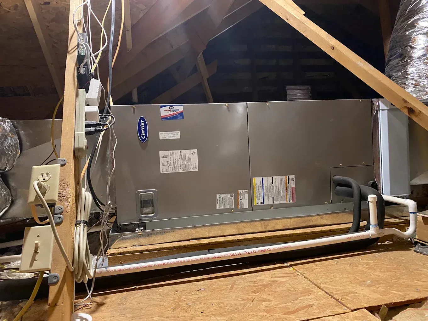 Attic HVAC unit with ductwork and insulation in a roof space
