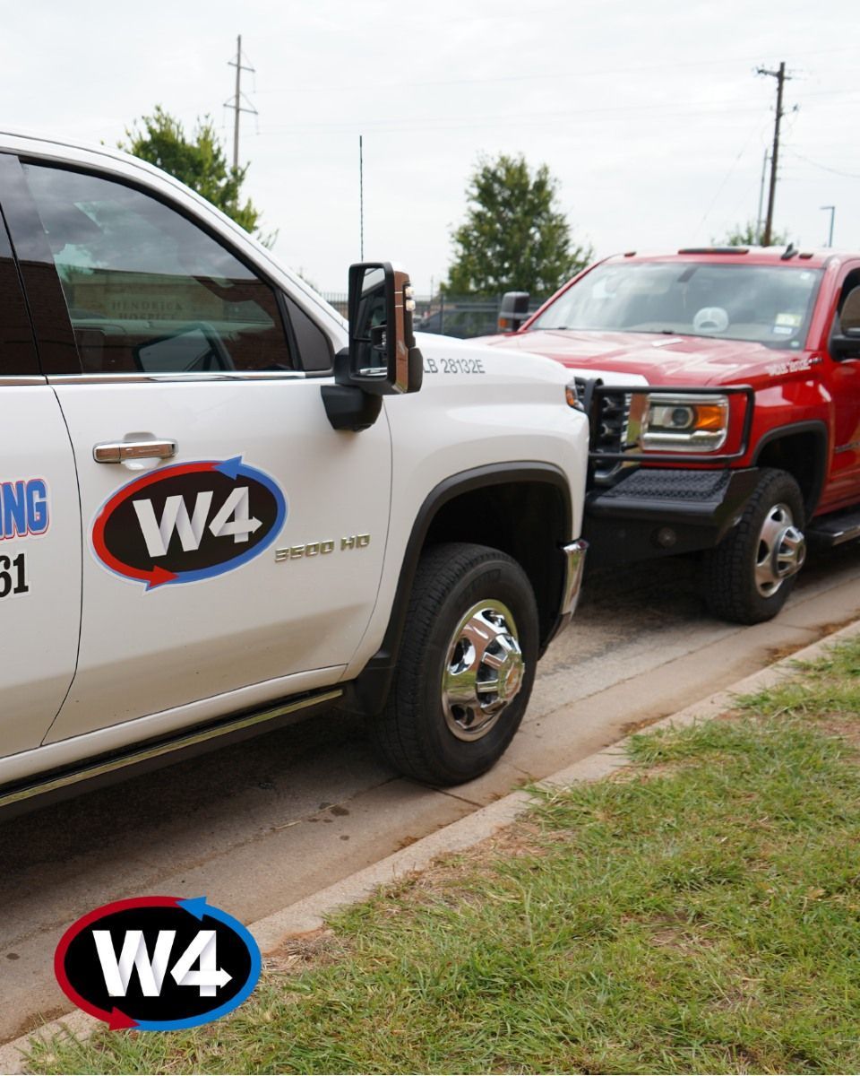 White and red W4 pickup trucks parked nose-to-nose along a curb in a grassy lot