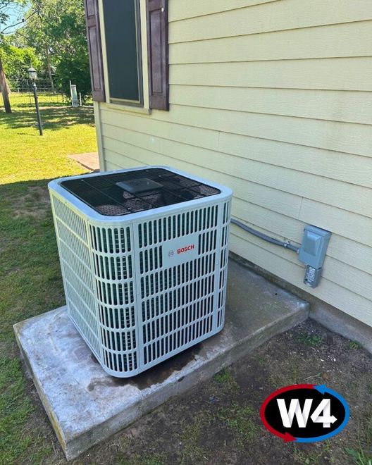 Outdoor air conditioner unit beside a house wall on a concrete pad, near a window and electrical box.