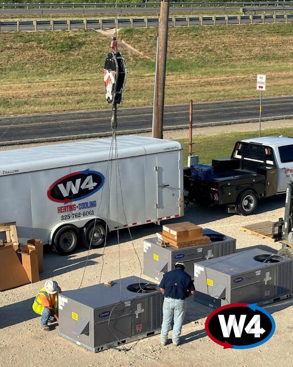 Workers load equipment beside W4 trailer and truck on a roadside work site