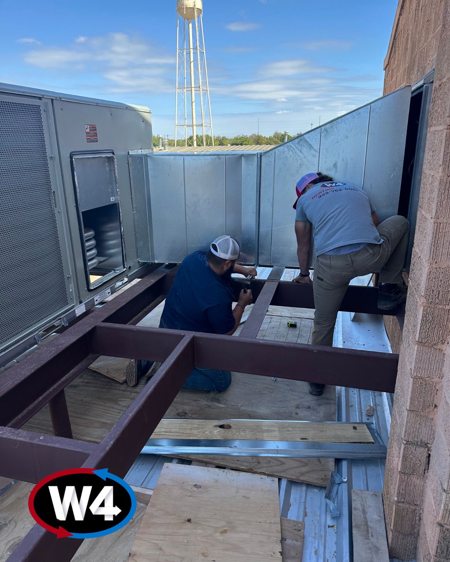 Workers on rooftop installing steel beams beside HVAC units under a blue sky.