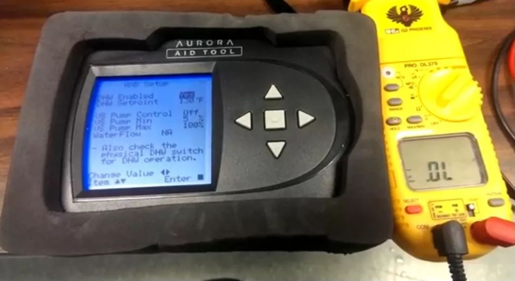 Blue handheld meter beside yellow digital multimeter on a wooden surface