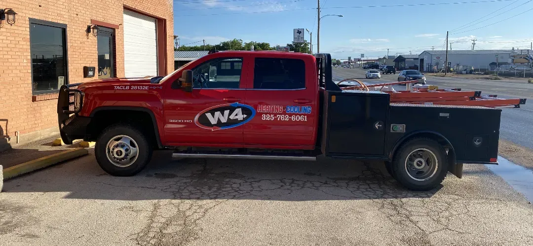 Red W4 service pickup truck parked beside a brick building on a sunny day.