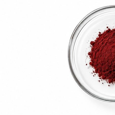 Glass bowl with a mound of red powder on a white background
