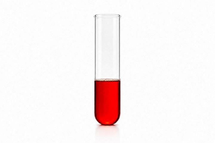 A clear glass test tube partially filled with red liquid on a white background
