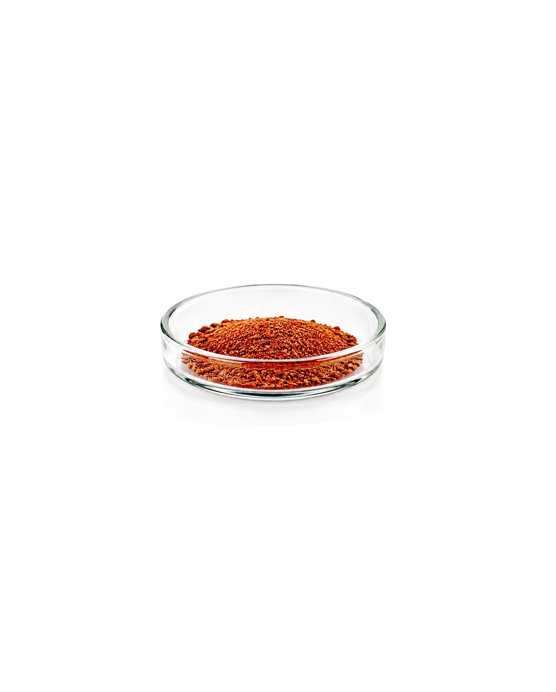 Shallow glass dish filled with red granules on a white background