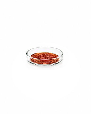 Shallow glass dish filled with red granules on a white background