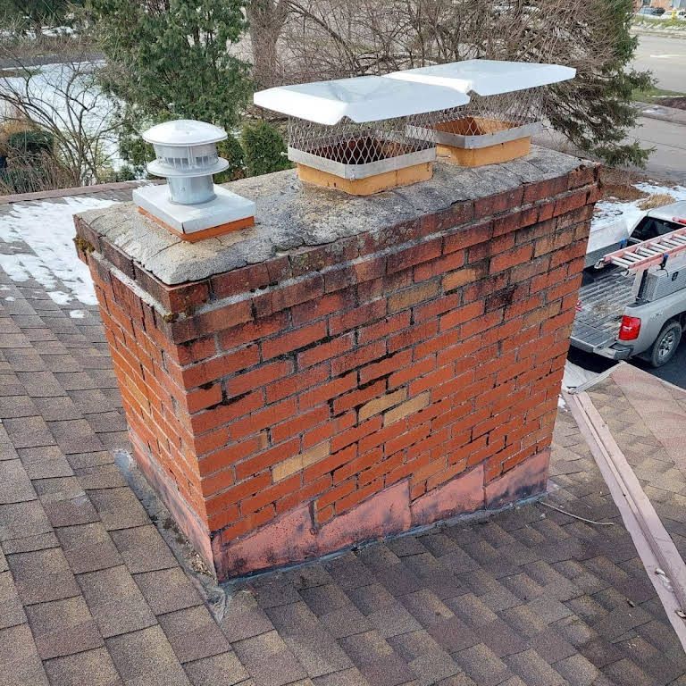 A brick chimney is sitting on top of a roof next to a truck.