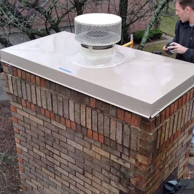 A man is standing on top of a brick chimney.
