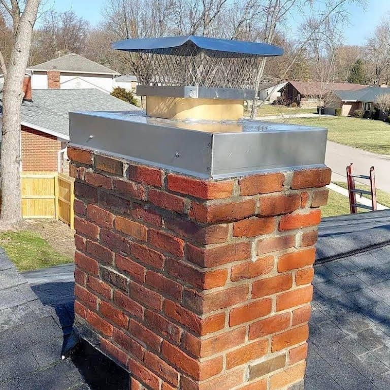 A brick chimney with a metal cap on top of it