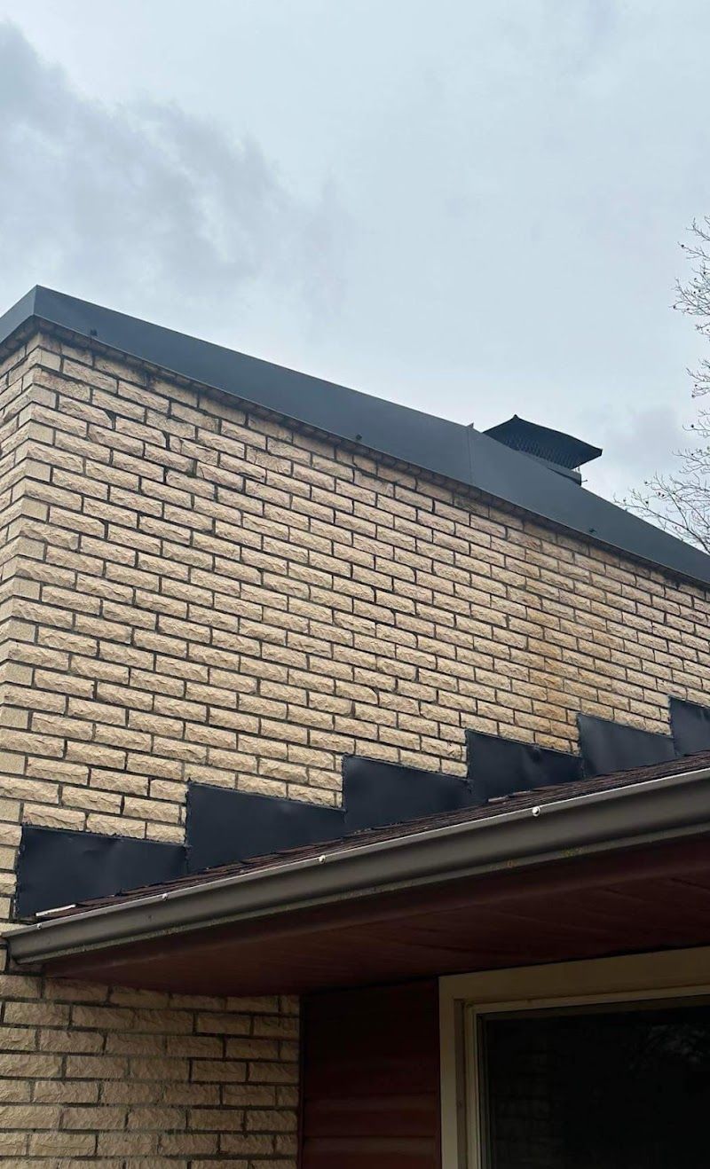 A brick building with a black roof and a chimney.