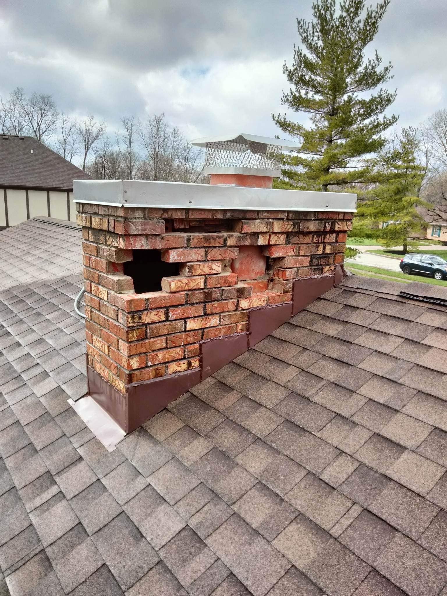 A brick chimney on top of a roof with a hole in it.