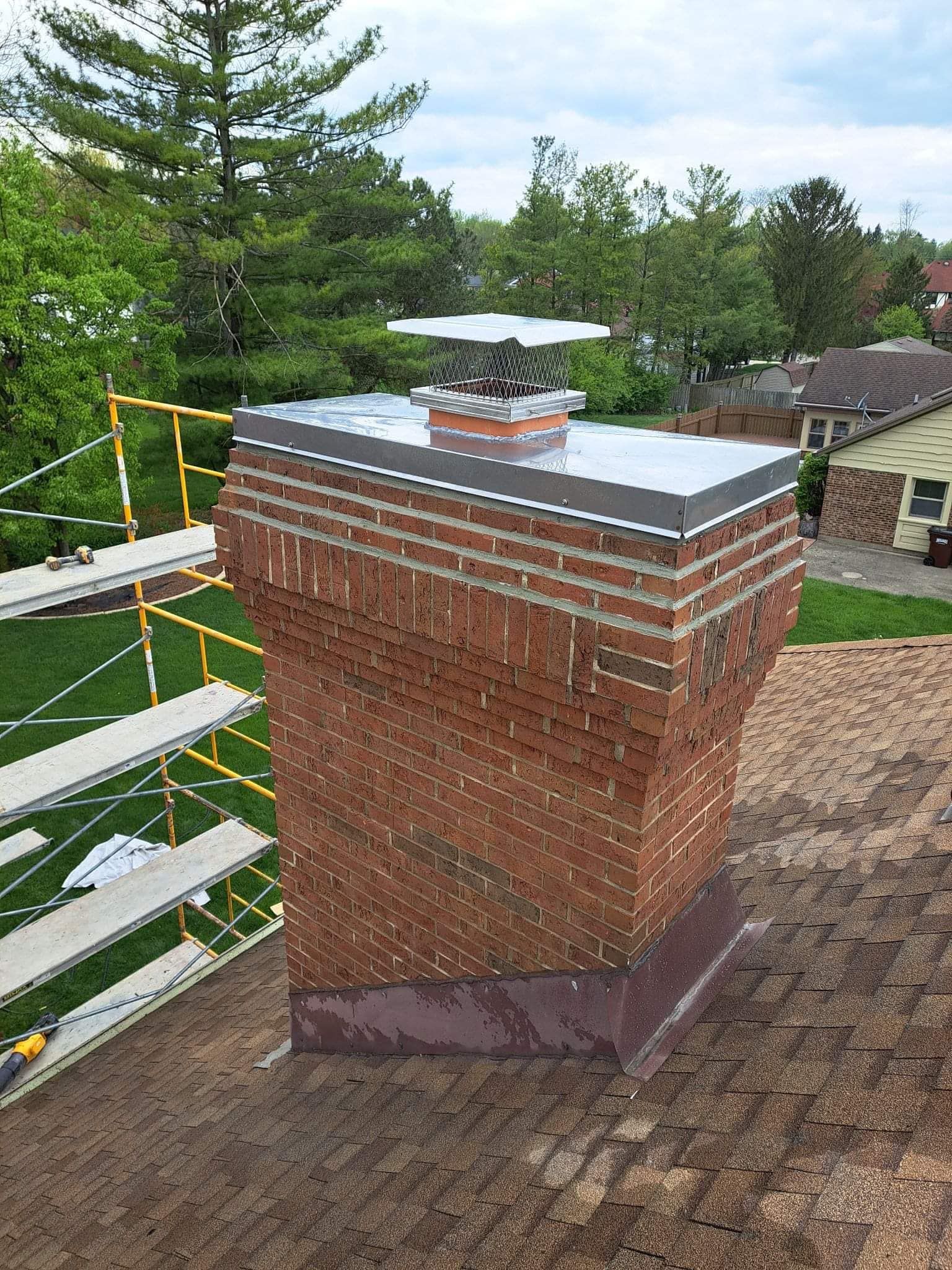 A brick chimney is sitting on top of a roof.