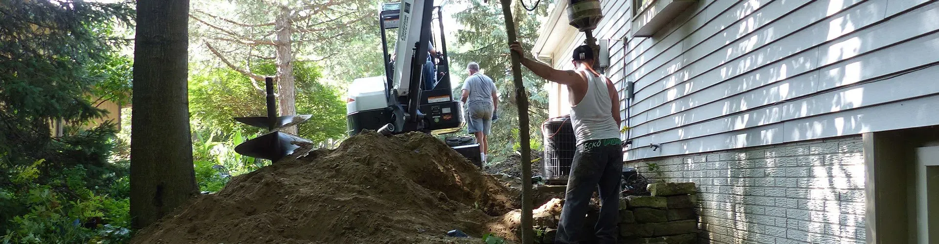 A man is standing next to a pile of dirt in front of a house.