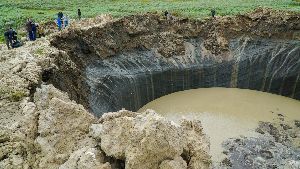 A large hole in the ground filled with water and rocks.