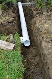 A white pipe is being installed in a trench.