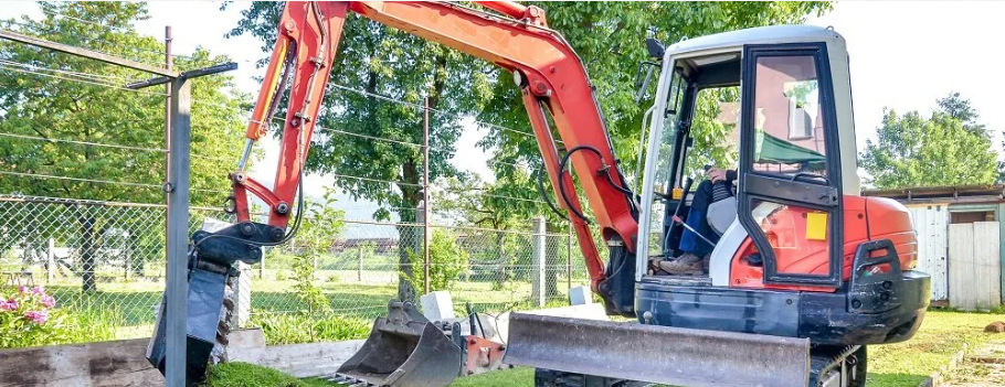 A man is using a small excavator to dig a hole in the ground.