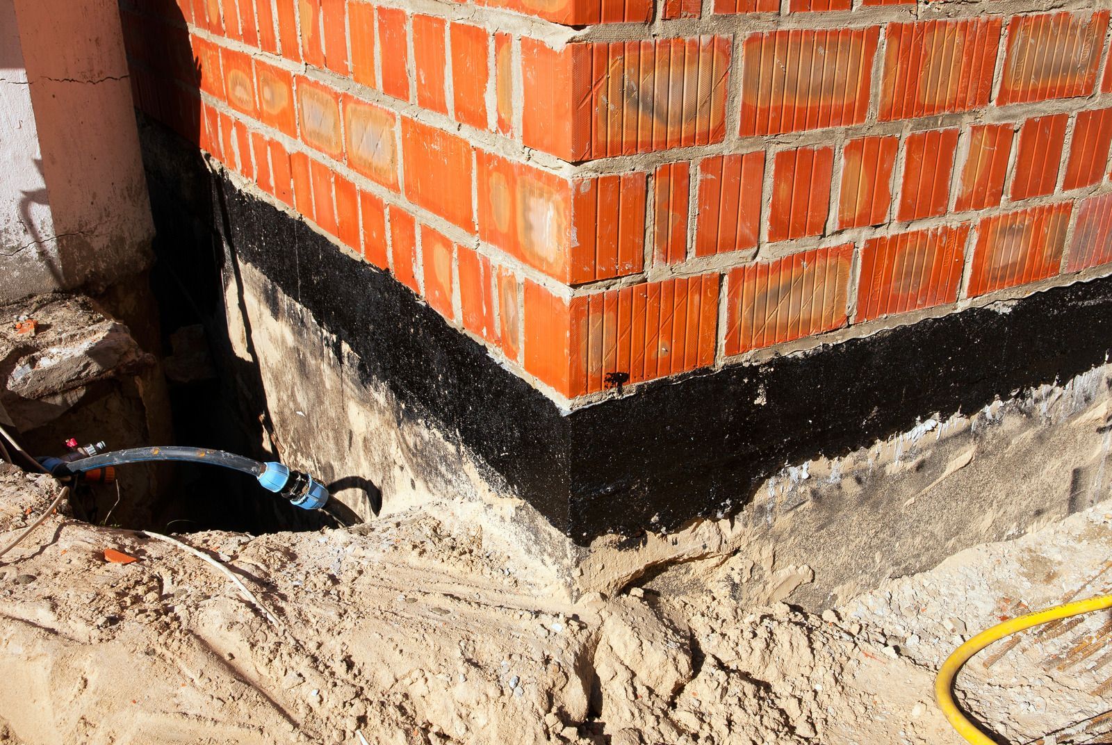 A brick wall with a black border and a yellow hose in front of it.
