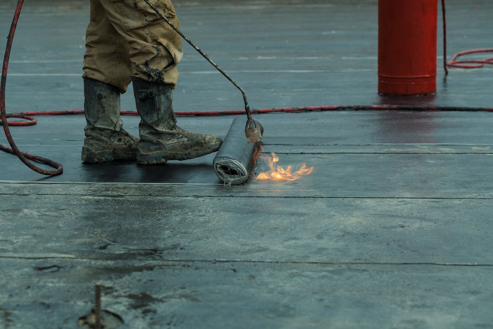 A man is cutting a piece of asphalt with a torch.