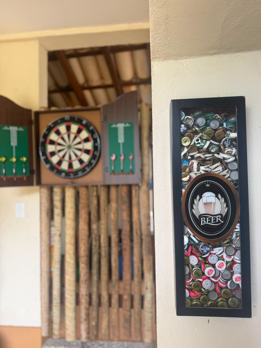 Alvo de dardos acima de um portão rústico de madeira, com um colorido enfeite de parede à direita, no interior.