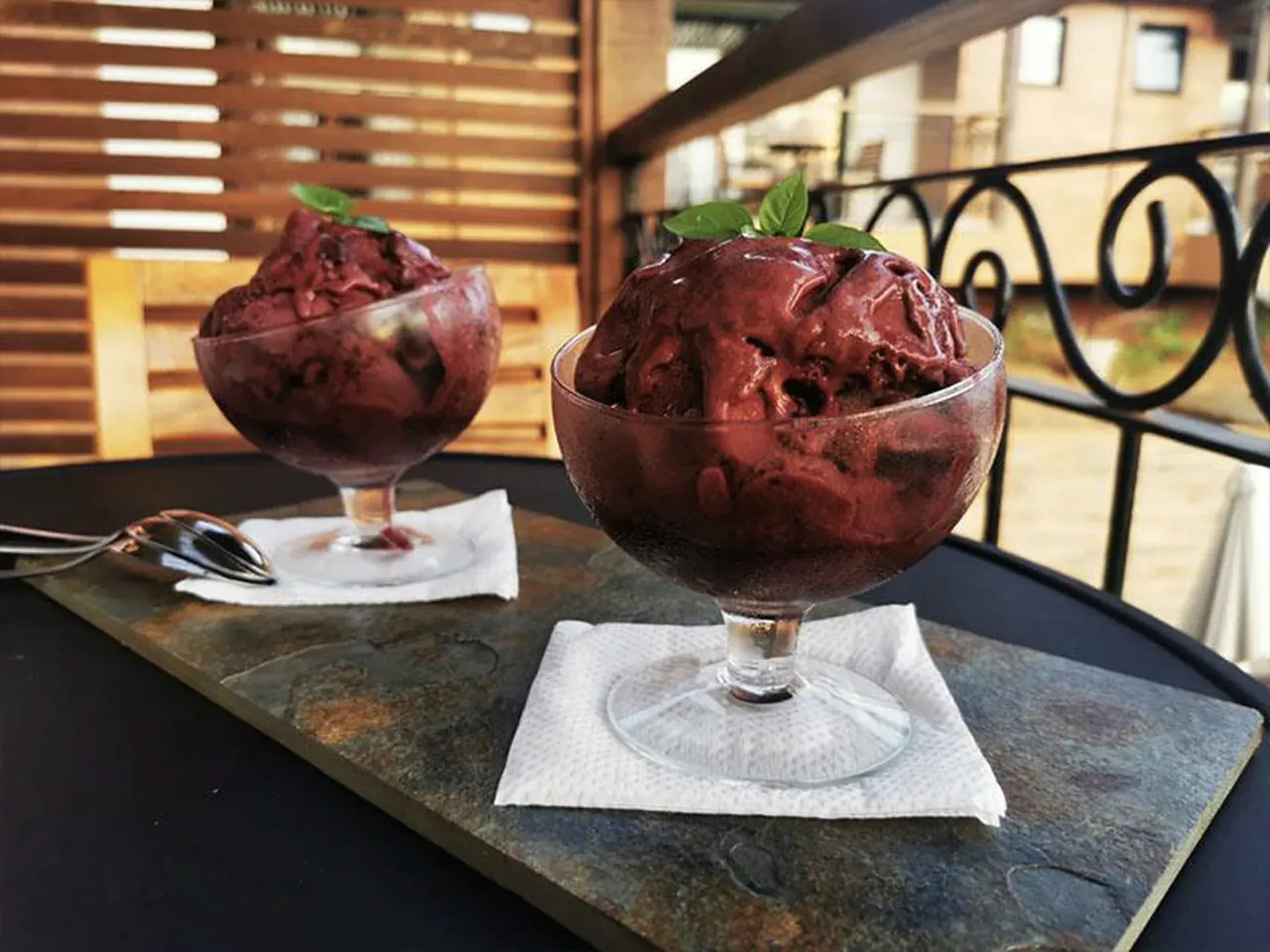 Duas taças de sobremesa de chocolate sobre guardanapos em cima de uma mesa perto da janela, com garfos ao lado.