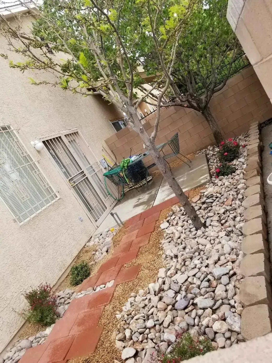 There is a tree in the middle of a rock garden in front of a house.