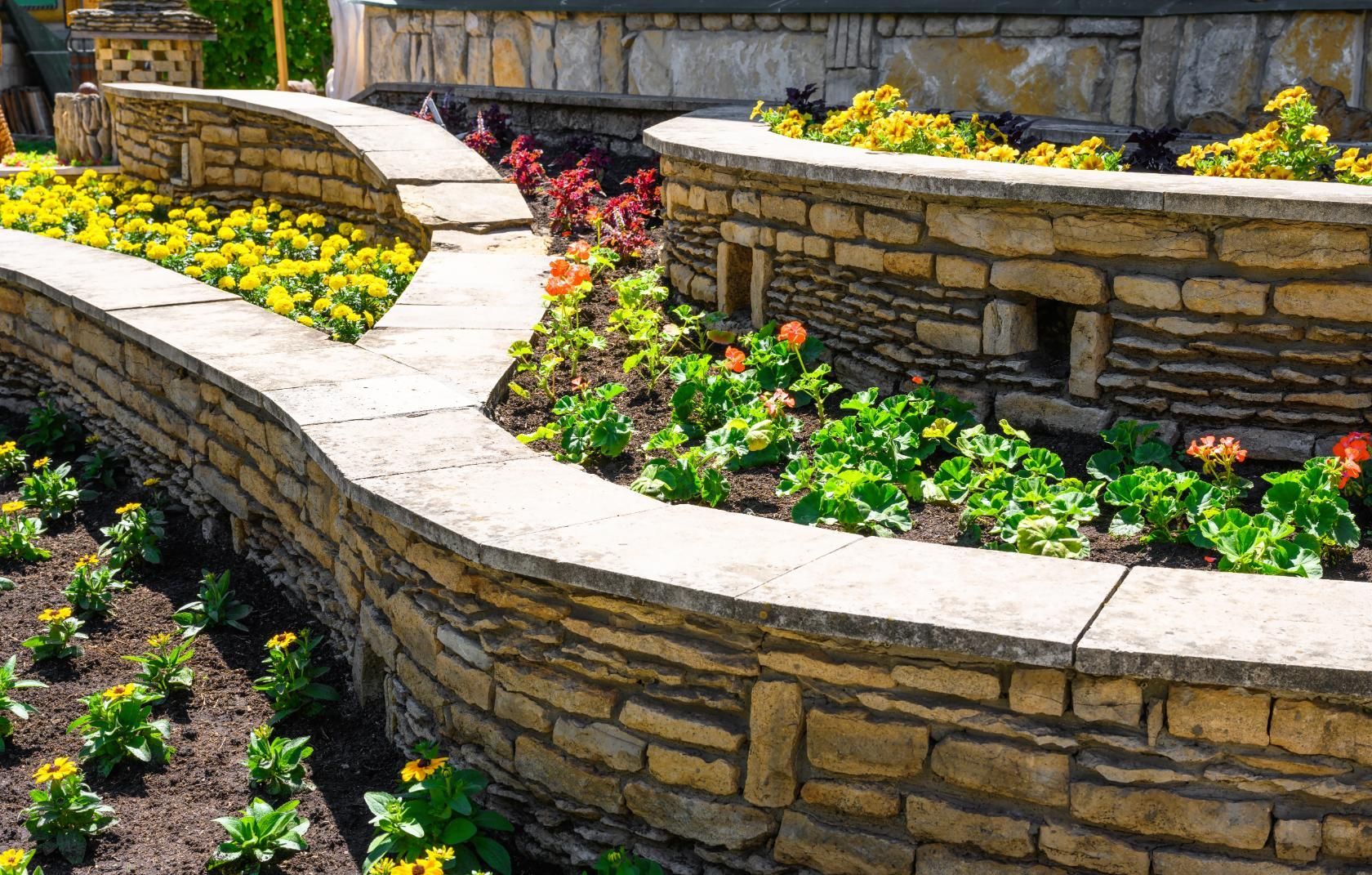 A stone wall surrounded by flowers in a garden.