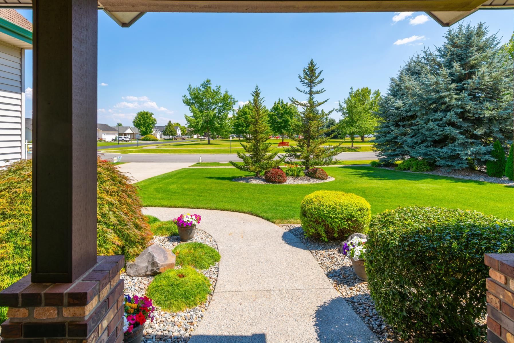 A view of a lush green yard from the porch of a house.