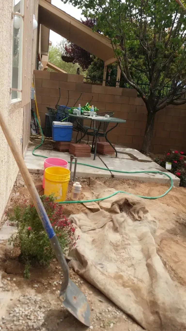 A shovel is sitting on the ground in front of a house.