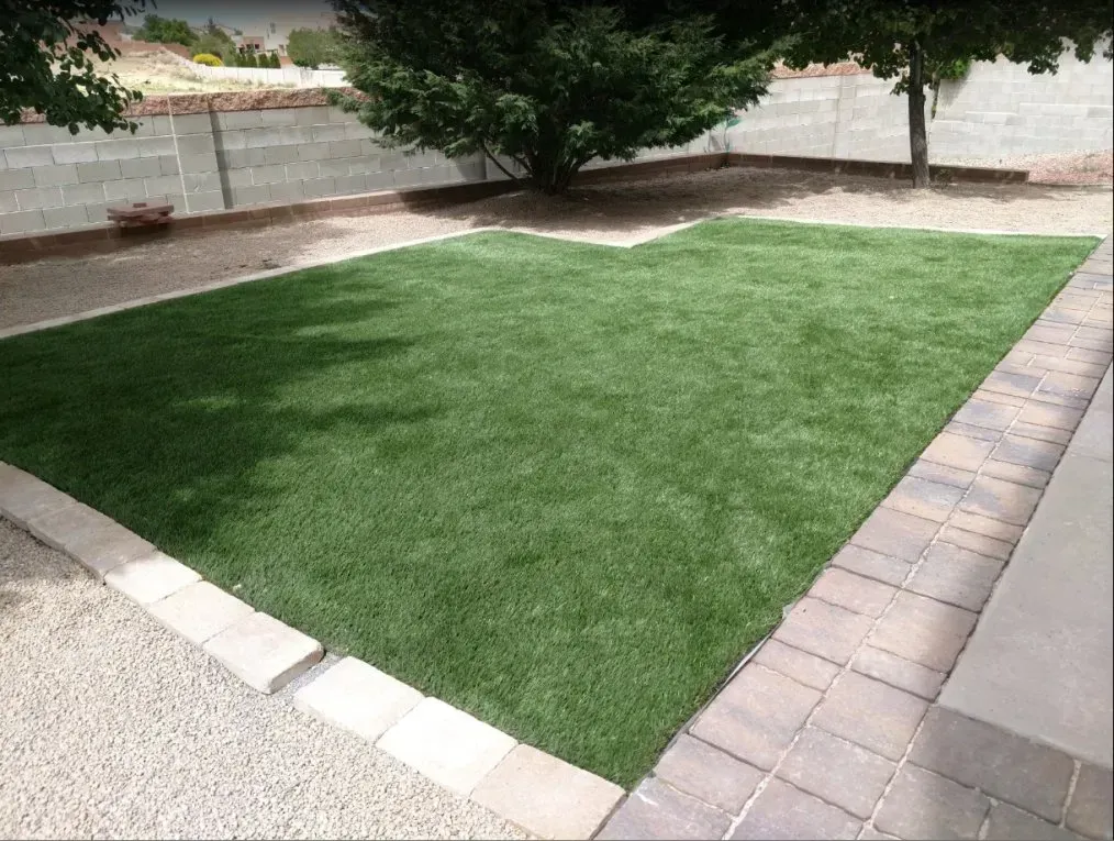 A lawn with a tree in the background and a brick walkway.