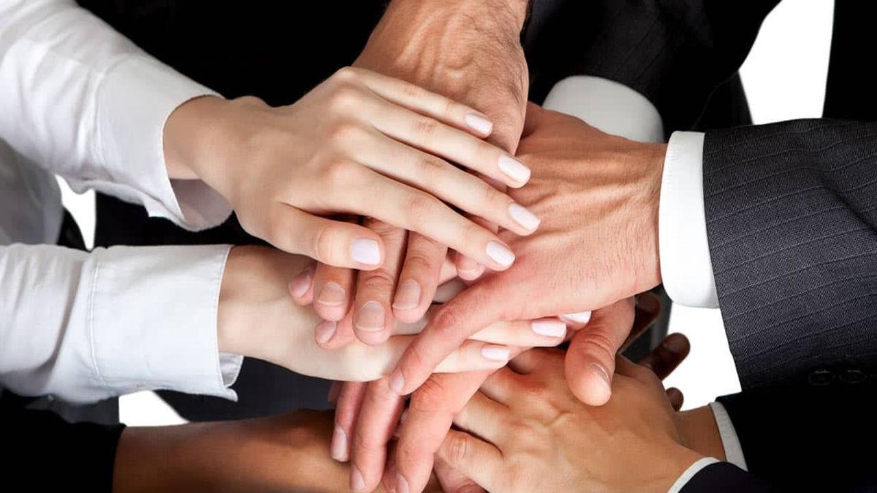 Hands stacked together in a team huddle, symbolizing unity and collaboration.