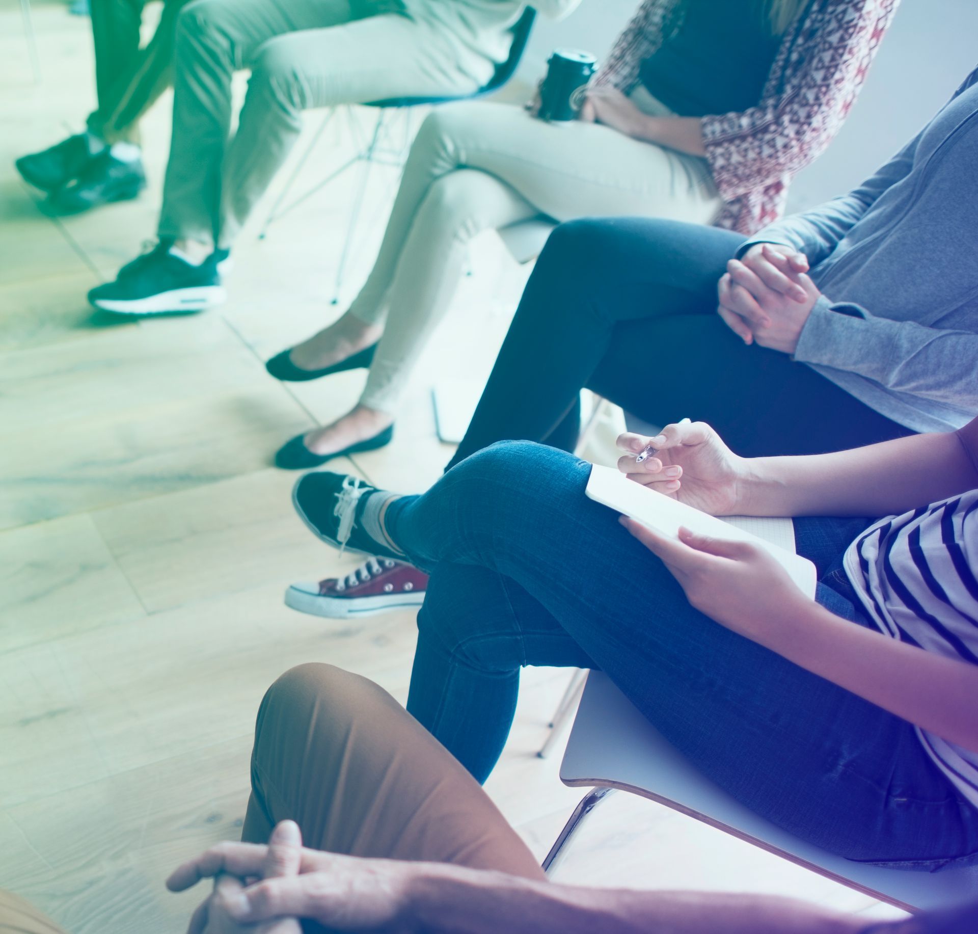 People seated in a bright meeting room, taking notes during a discussion