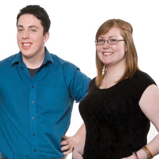 Two smiling people standing against a white background, one in a blue shirt and one in a black top.
