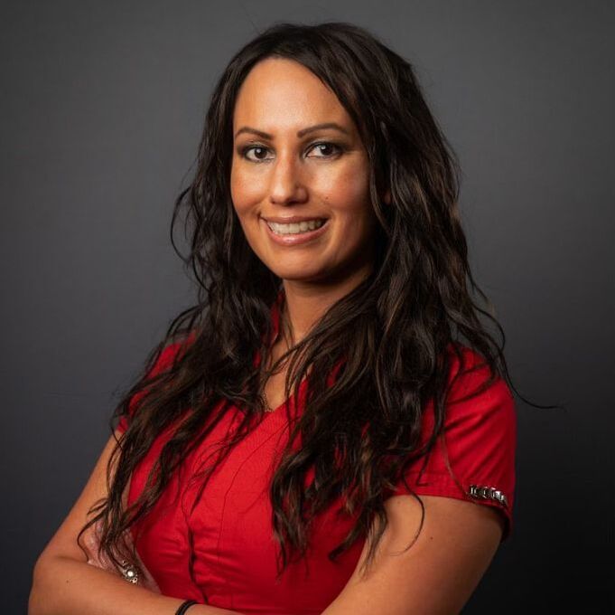 Woman in a red top smiling against a dark gray background