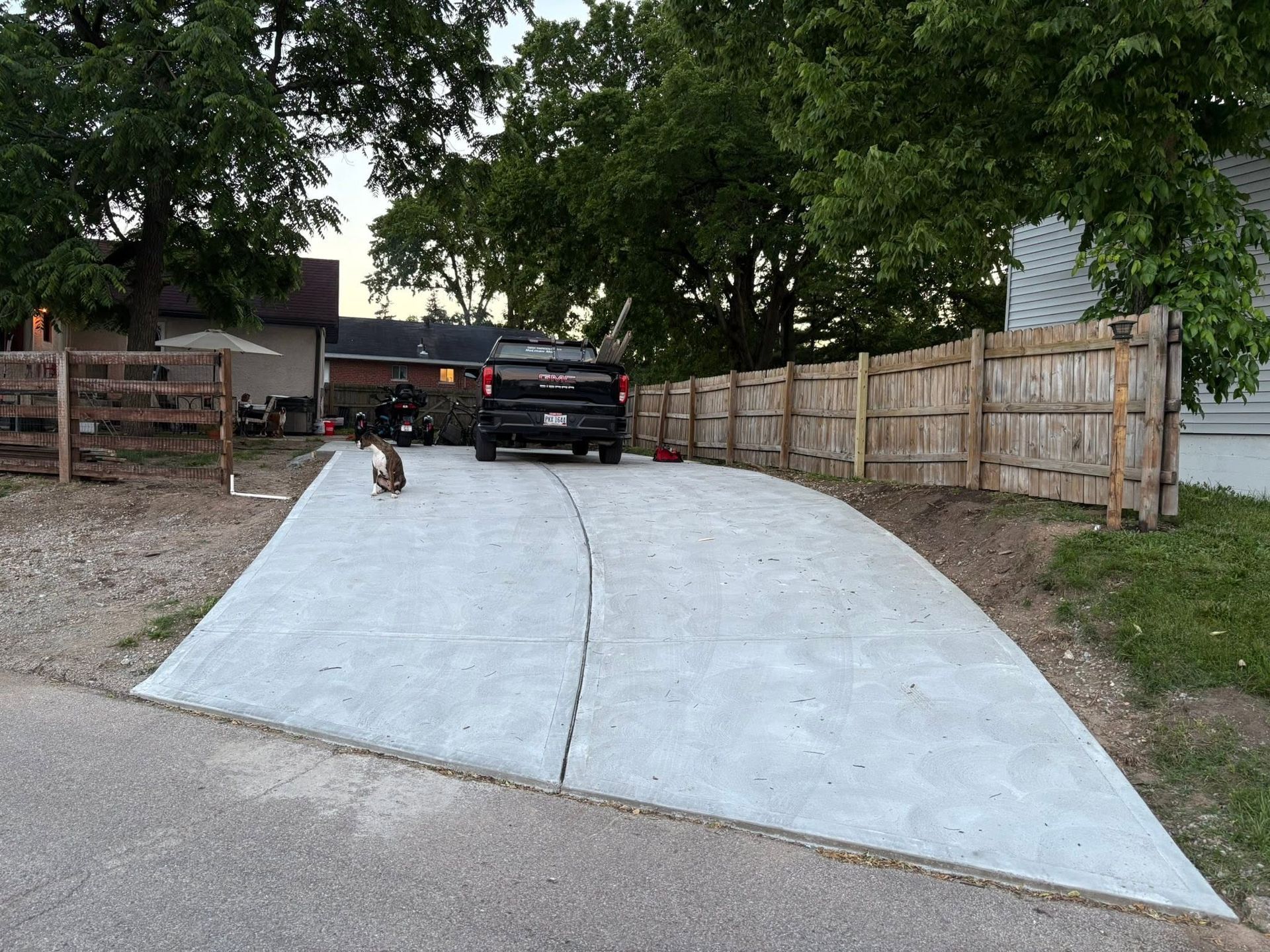 Concrete driveway with a black truck parked at the top and a small dog near the center.