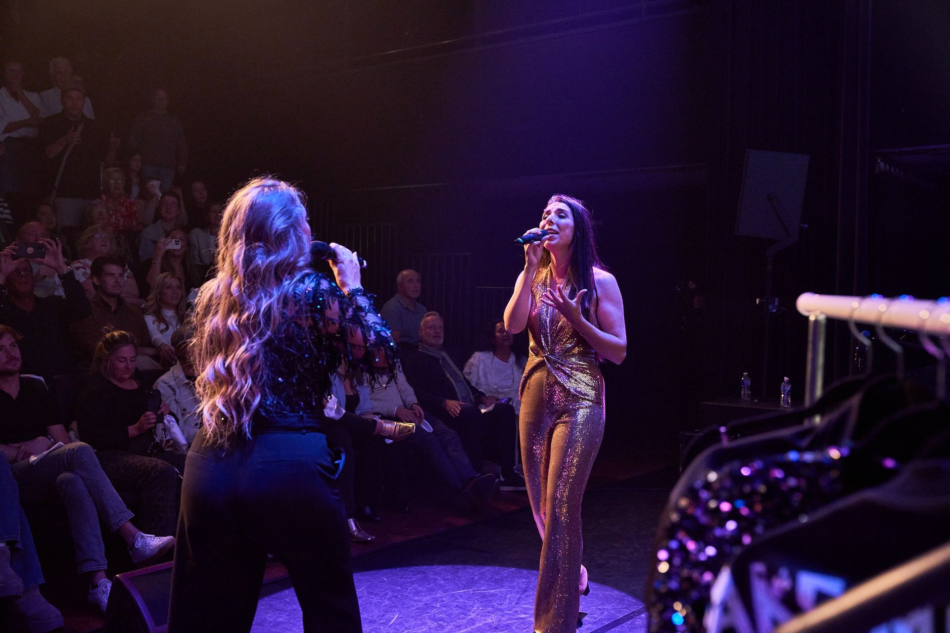 Zangduo Remedy zingt op het podium, een van hen in een gouden outfit onder paarse lichten, terwijl het publiek toekijkt tijdens hun theatershow in het Isala Theater in Capelle ad IJssel