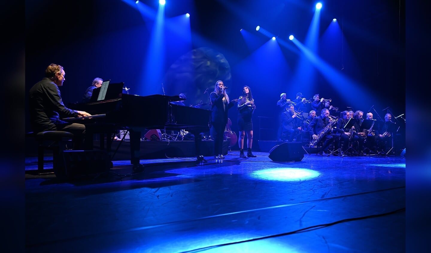 Zangduo Remedy met bigband in blauw licht met een pianist en orkest op het podium van het Isala Theater in capelle ad IJssel