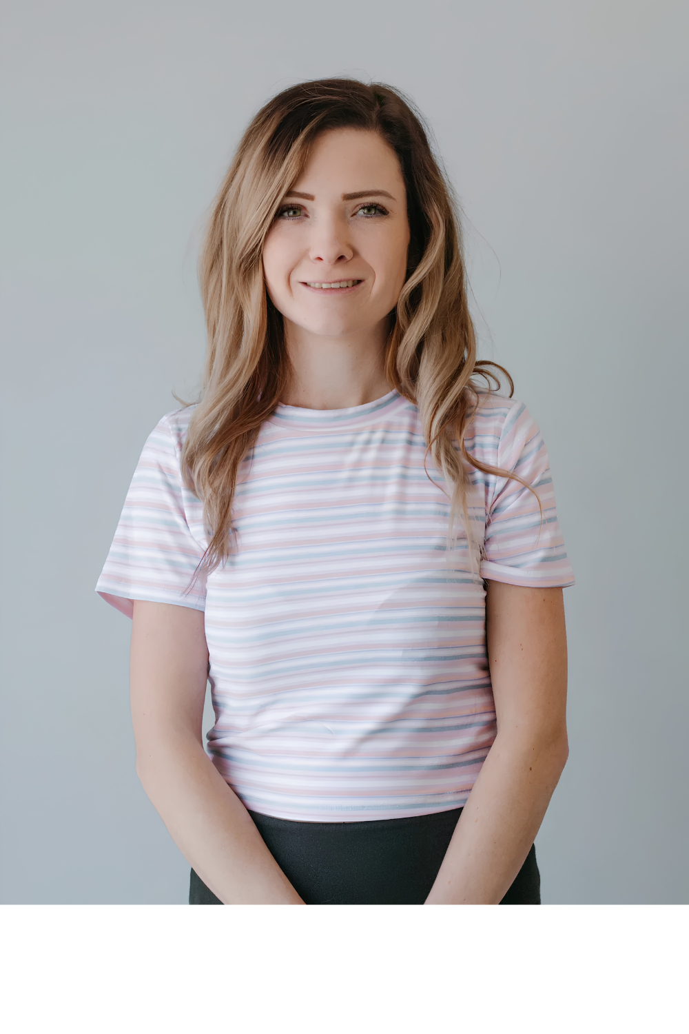 Smiling person in a white striped T-shirt standing against a light gray background
